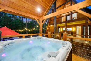 Private outdoor hot tub on covered deck at Wolf and Wander Mars Hill NC with string lights and wooded views at dusk