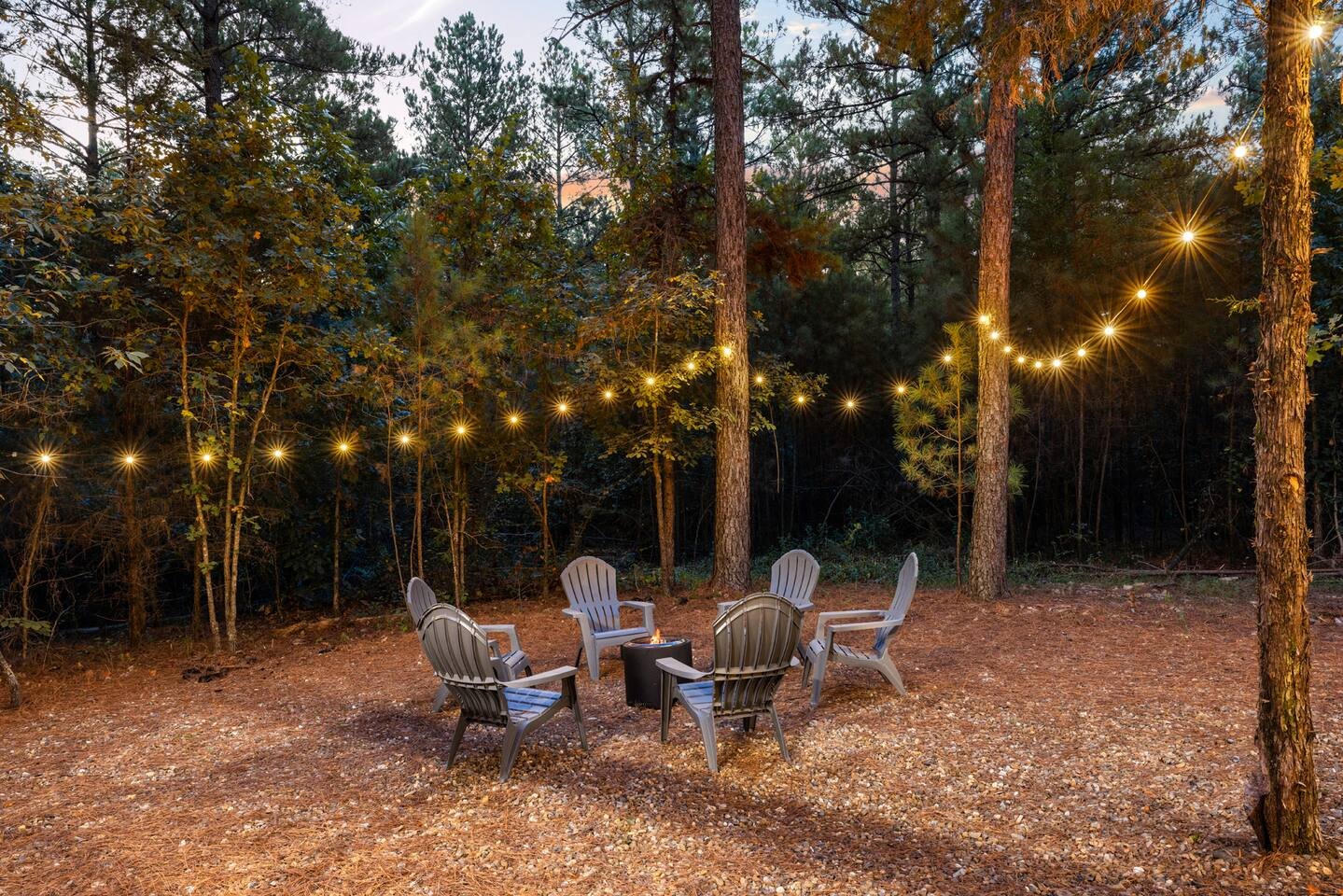 luxury cabin in Broken Bow outdoor fire pit seating area under string lights in pine forest